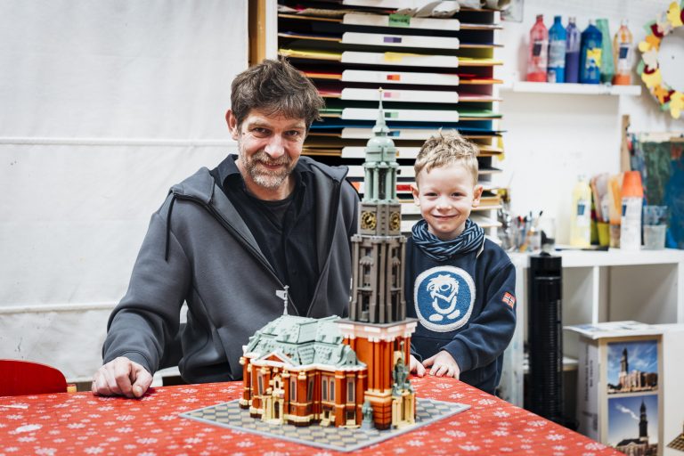 Theo und Adreas stehen vor einem Michel-Gebäude aus Lego-Steinen