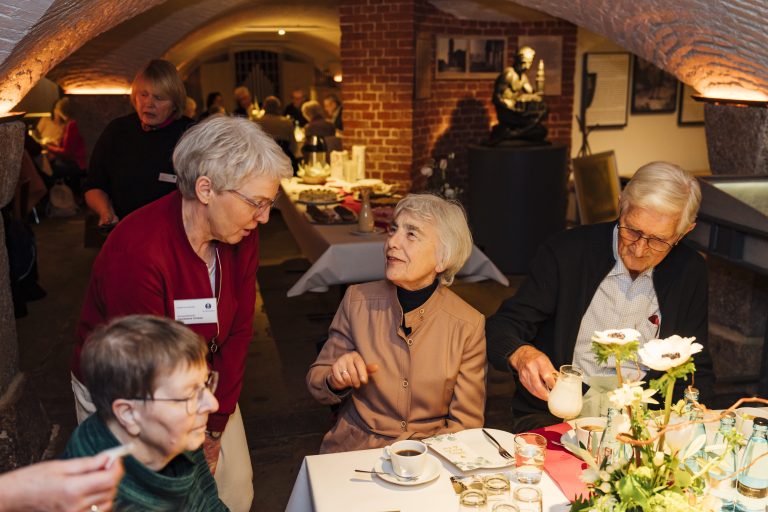 In der Krypta sitzen Stifterinnen und Stifter bei Kaffee und Kuchen zusammen.